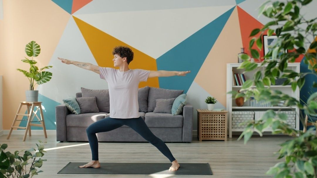 Person gör en stående stretchövning på en yogamatta i vardagsrummet
