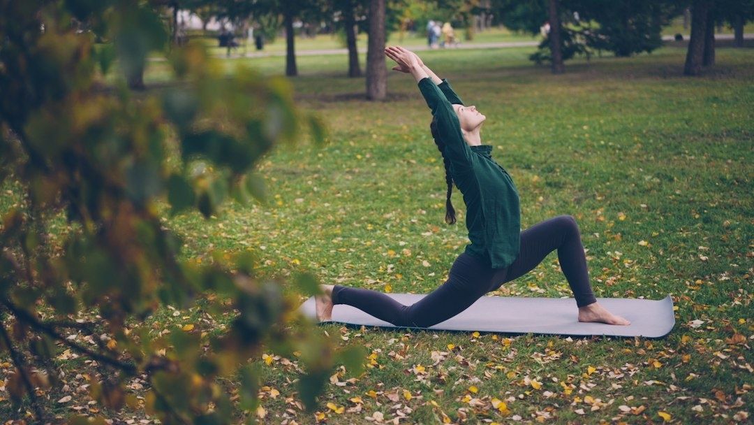 Person stretchar på en yogamatta i en höstlig park