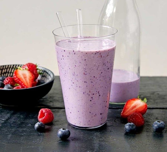 Lila bärsmoothie i glas med jordgubbar, hallon och blåbär